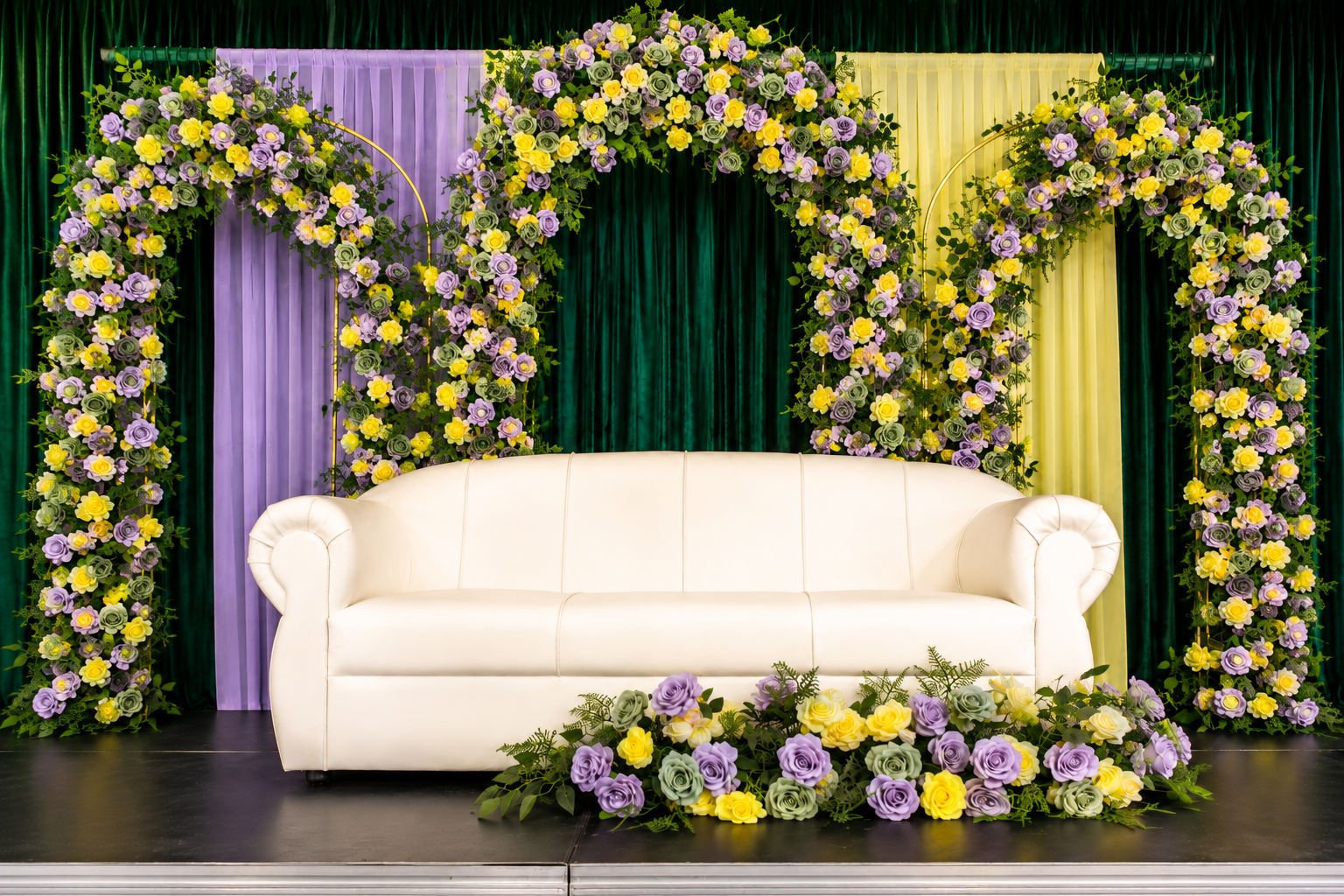 Lavender and yellow floral wedding stage setup with white sofa and layered arches